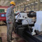 An SME worker is operating the metal working equipment